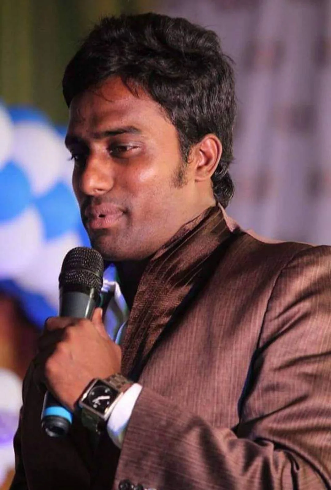 Pavan speaking on stage with a microphone
